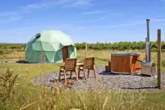 Taurus geodome exterior with private seating area and wood-fired hot tub