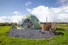 Aries geodome exterior with wood-fired hot tub and outdoor seating
