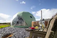 Aries geodome exterior with wood-fired hot tub and outdoor seating