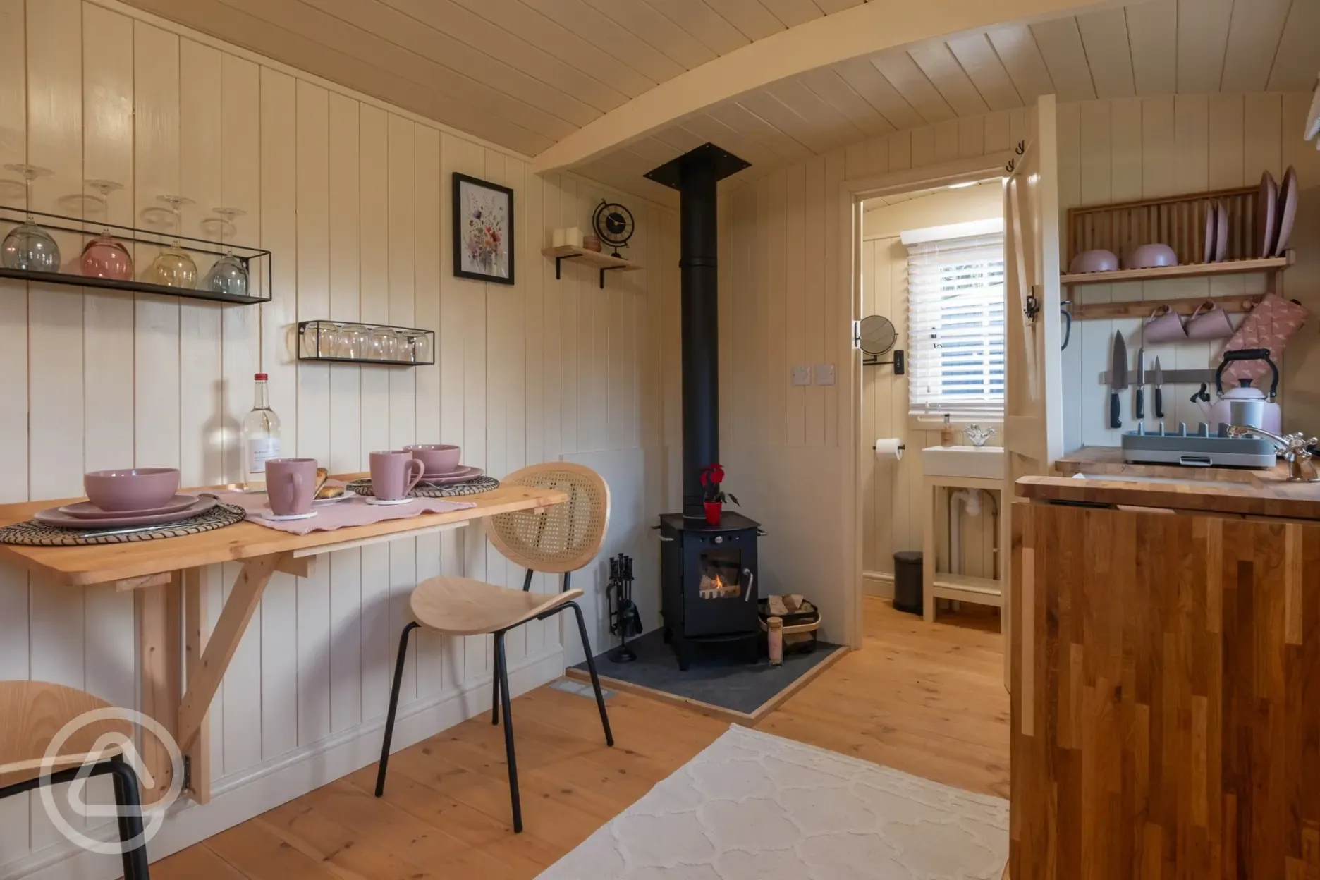 Furnished shepherd's hut interior with dining table, kitchenette, and fire place