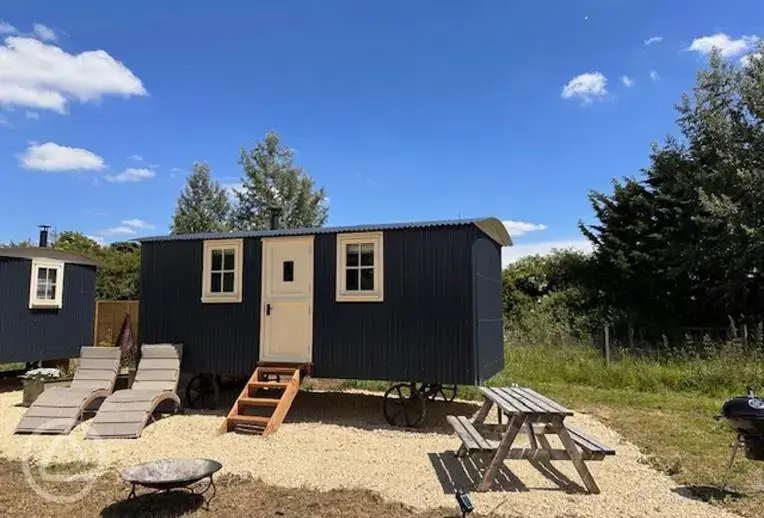 Shepherd's huts with sun loungers, a picnic table, and fire pit 