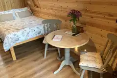Bracken pod interior with a double bed, table and chairs