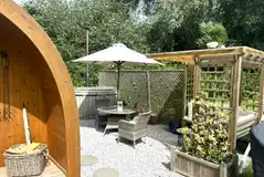 Willow glamping pod with a pergola seating area, table, chairs and hot tub
