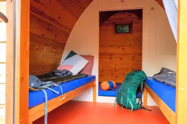 Camping pod interior with a double mattress and two single beds