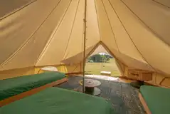 Bell tent interior with futon mattresses and furniture