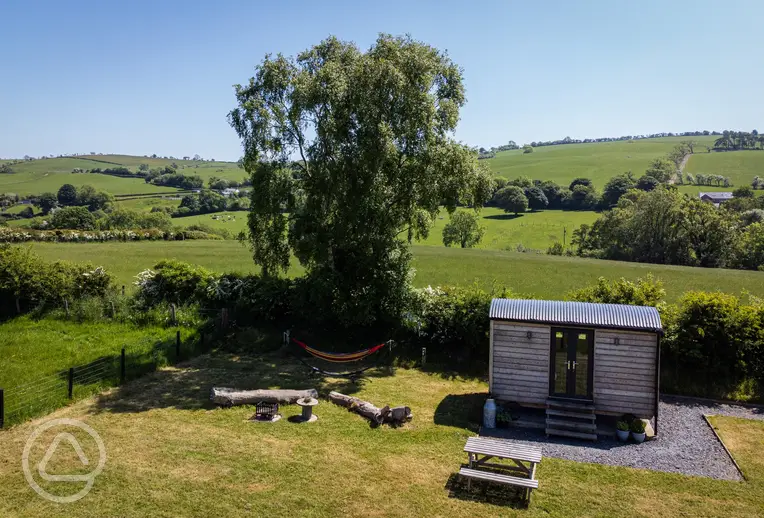 Aerial of the shepherd's hut, outdoor seating area, and hammock at Cae Main 