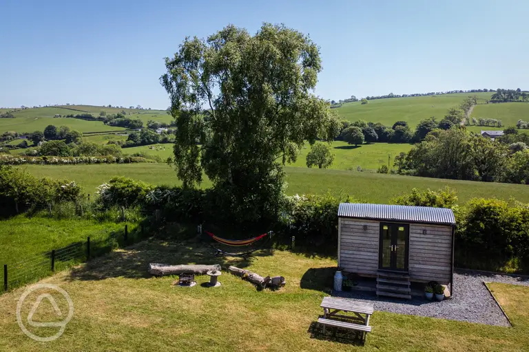 Aerial of the shepherd's hut, outdoor seating area, and hammock at Cae Main 