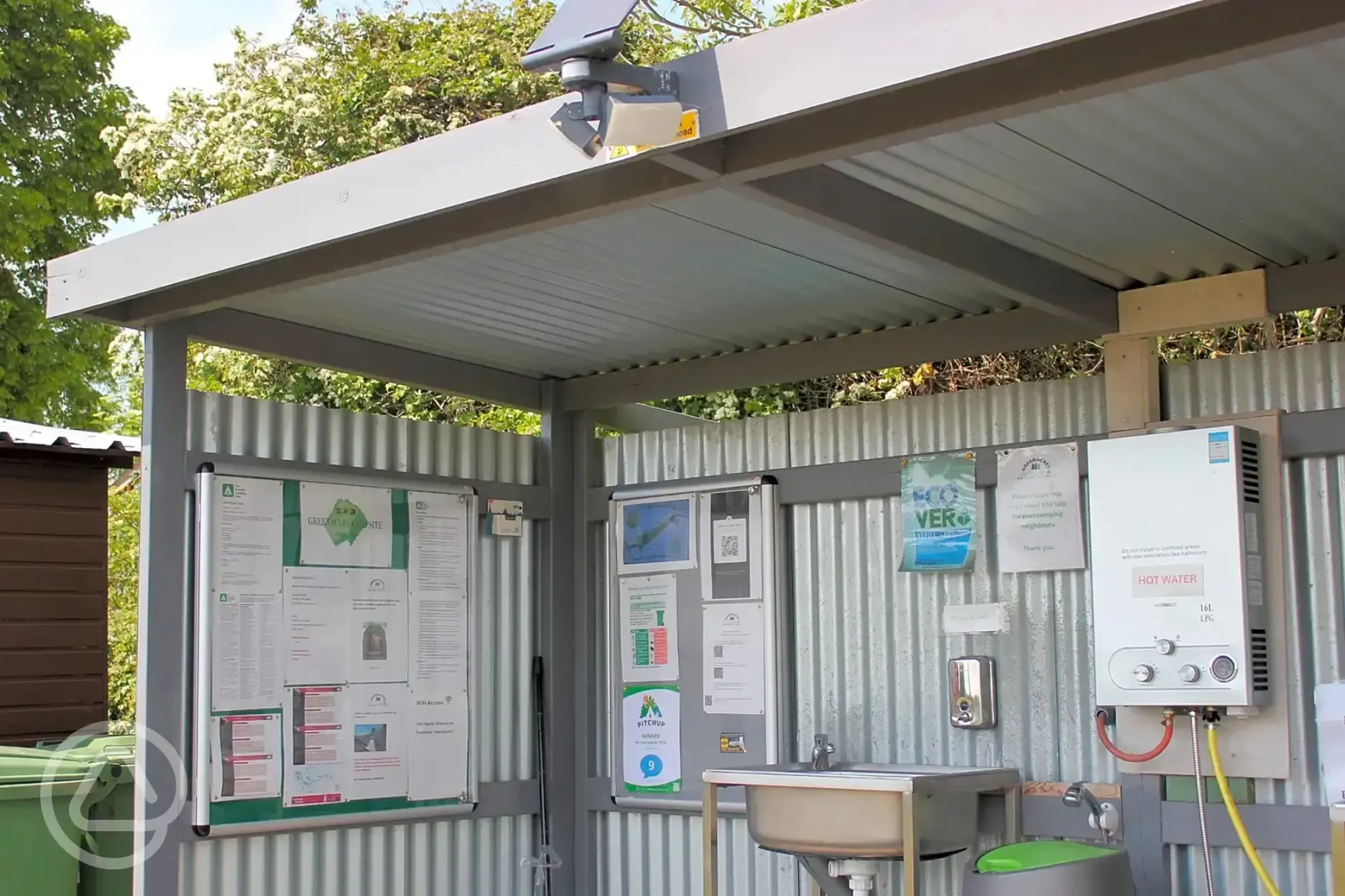 Outside washing up area with a notice board and leaflets