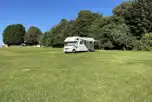 A campervan with an awning on the grass touring pitches with optional electric