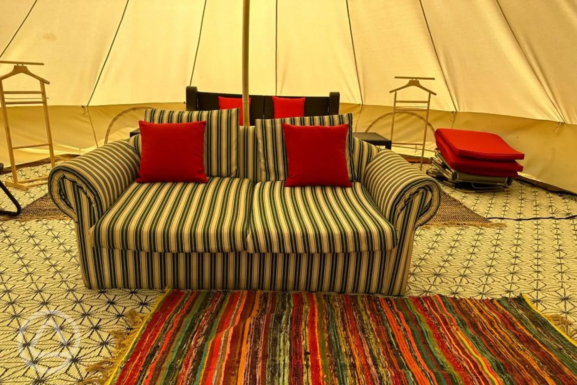 Bell tent interior with clothing hangers and a sofa