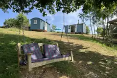 View of the two Valley ensuite shepherd's huts and the outdoor swing View of the two Valley ensuite shepherd's huts and the outdoor swing