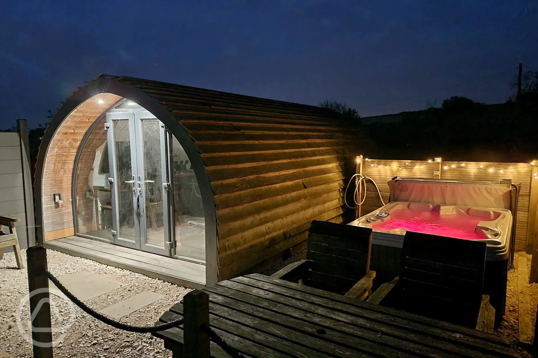 Squirrel glamping pod and hot tub at night