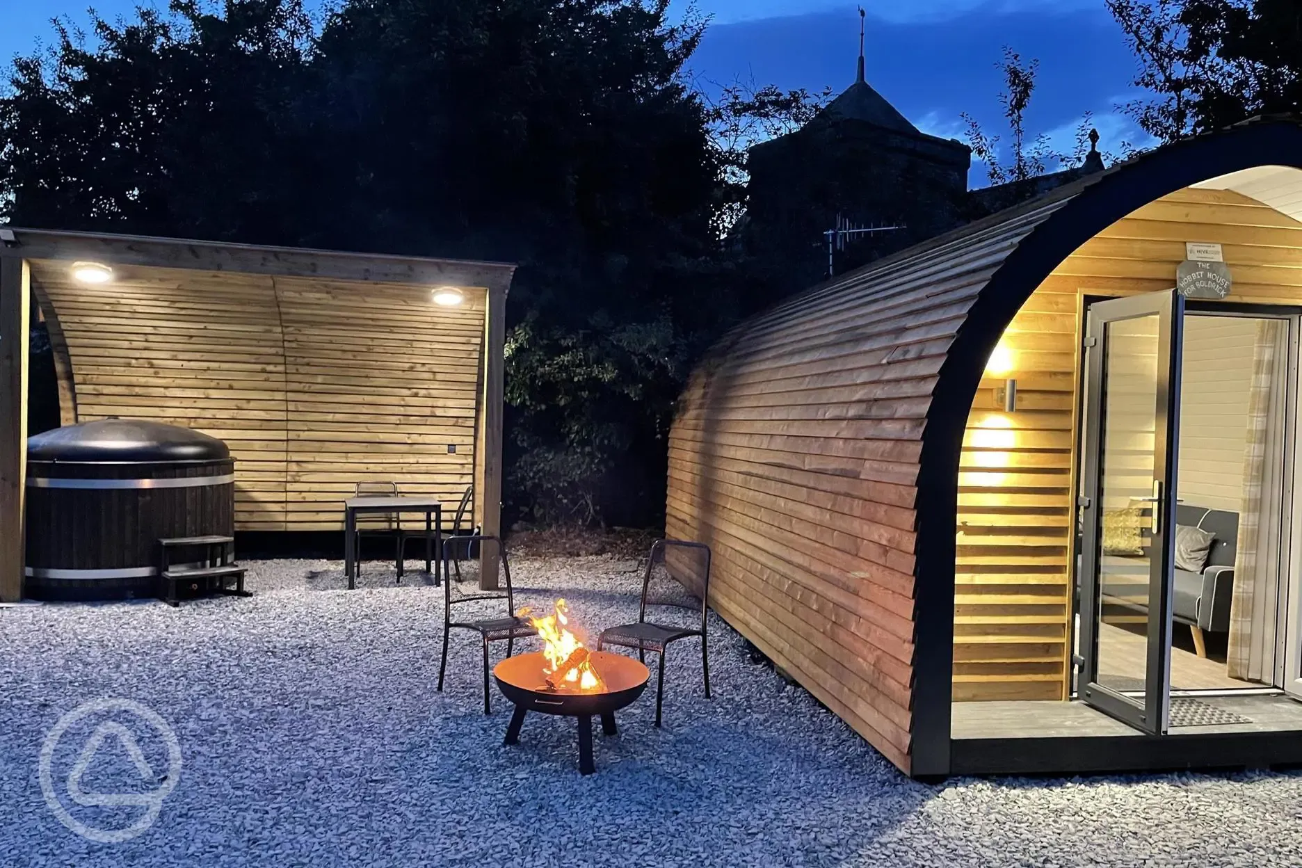 Glamping pod at night with woodfired hot tub and fire pit 