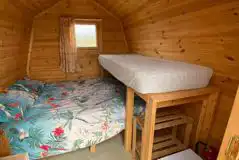 Log pod interior with double bed and bunk bed