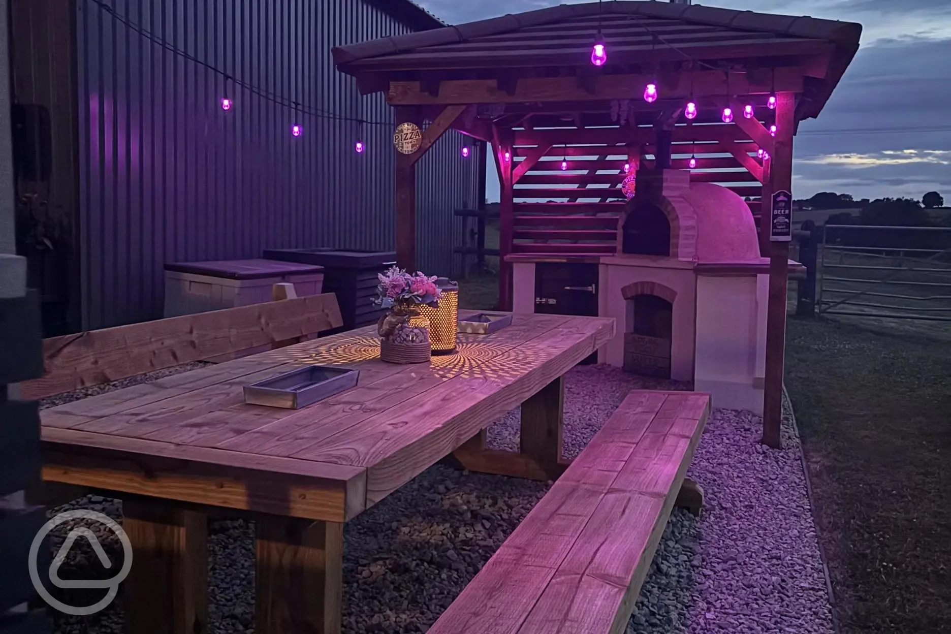Communal kitchen and dining area outdoor seating and pizza oven at night