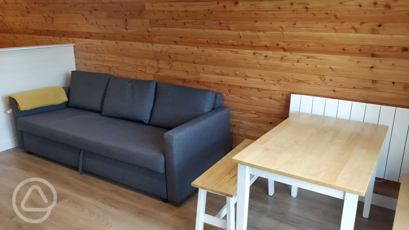 The Den and Roost glamping pod seating and dining area with sofa bed