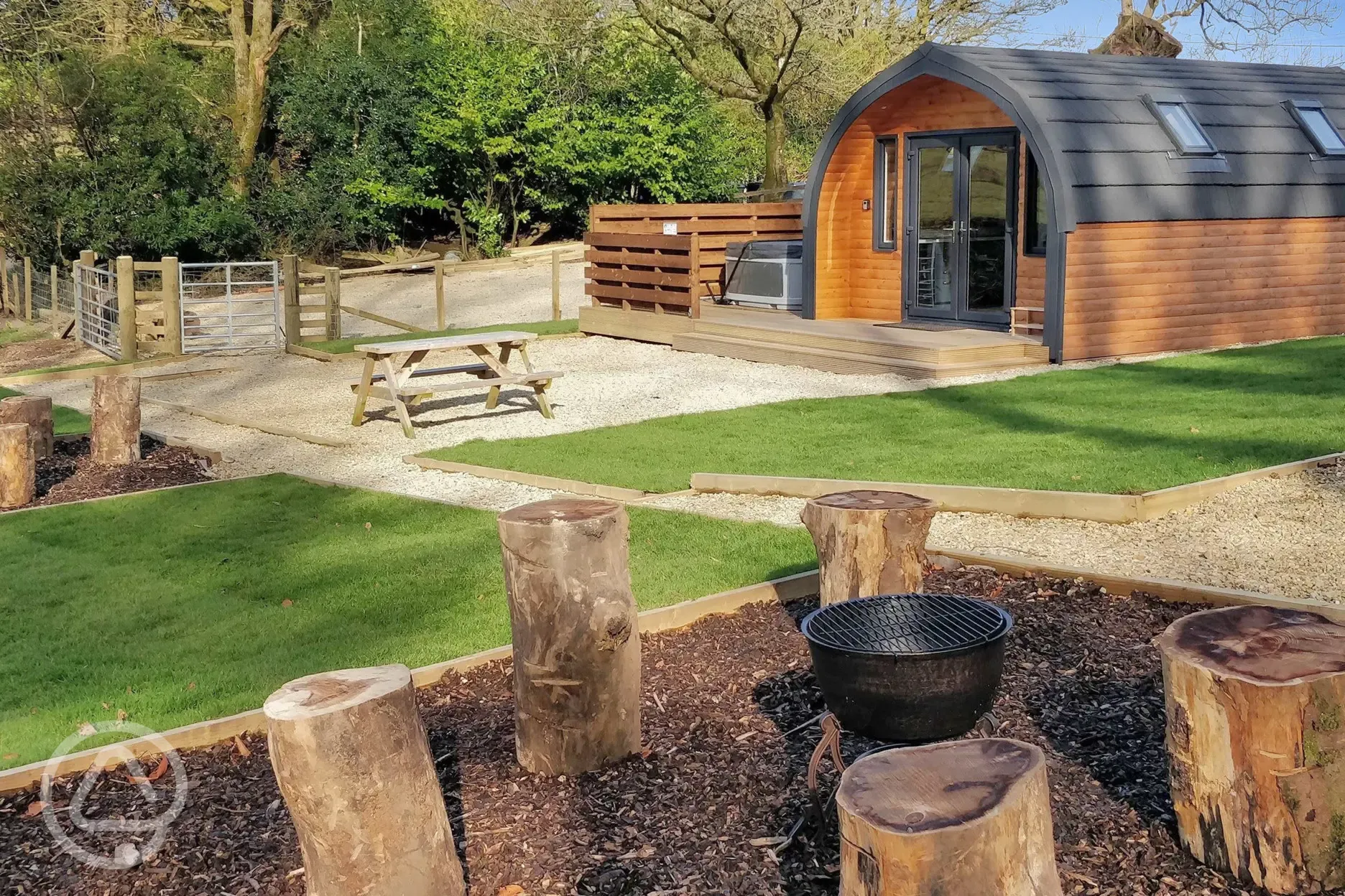 The Den glamping pod exterior with private hot tub, outdoor seating and fire pit