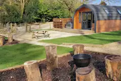 The Den glamping pod exterior with private hot tub, outdoor seating and fire pit