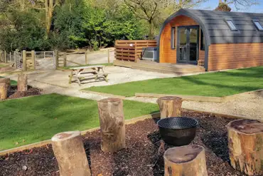 The Den glamping pod exterior with private hot tub, outdoor seating and fire pit