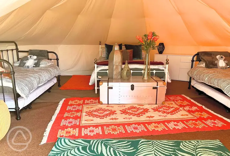 Bell tent interior with a double bed, two single beds and two trundle beds