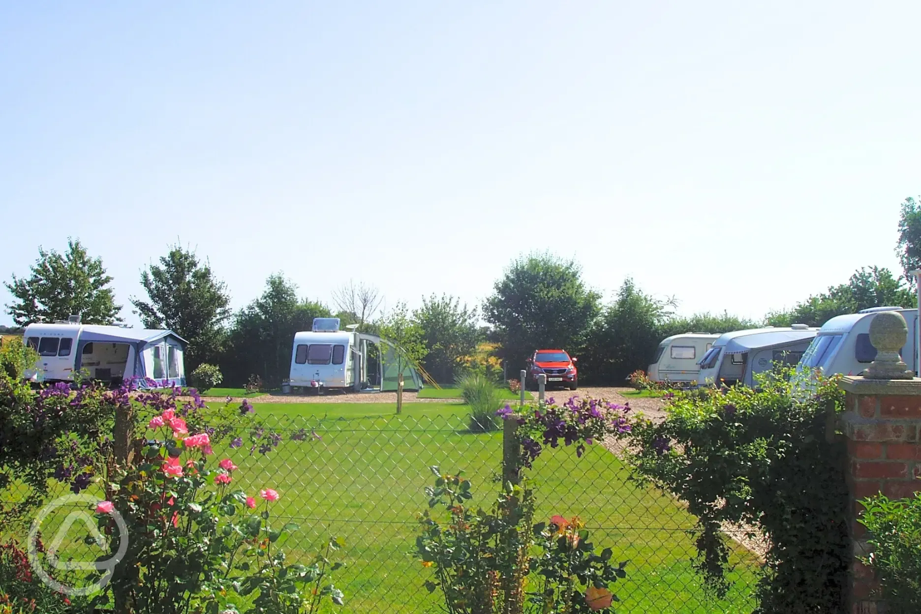 View over the fence of the electric hardstanding pitches at Pear Tree Cottage
