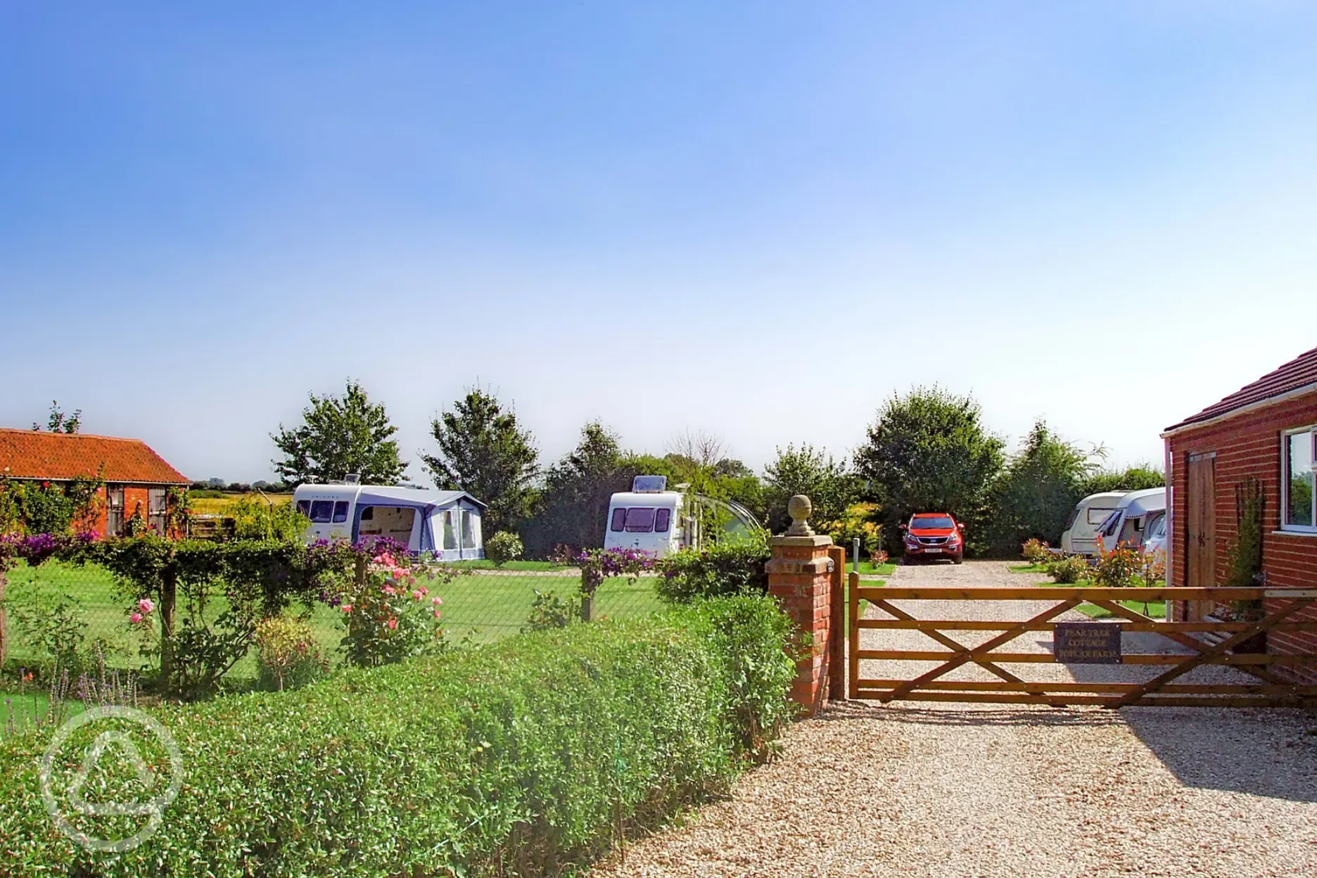 View over the gate of the electric hardstanding pitches at Pear Tree Cottage