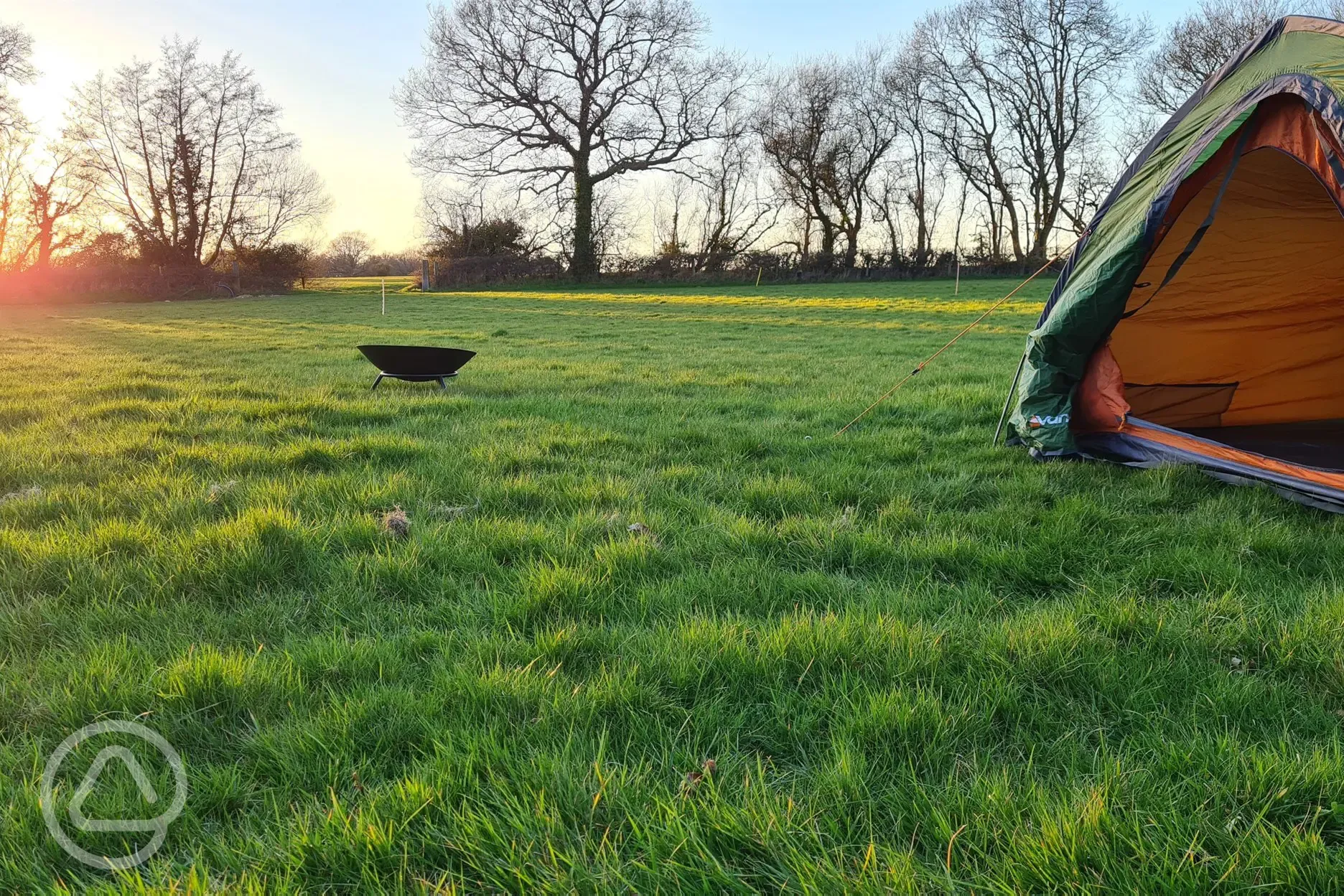 Grass tent pitches at sunset