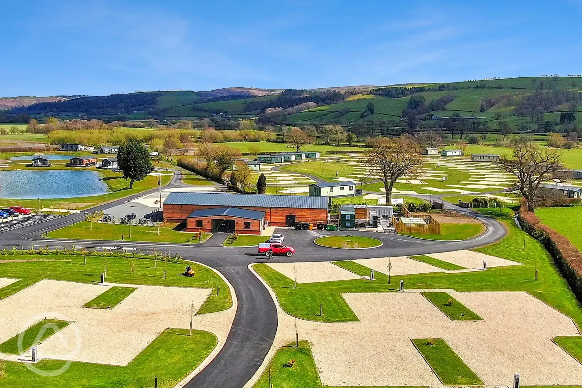 Aerial of Meadow Springs and touring pitches beside lake for watersports Aerial of Meadow Springs and touring pitches beside lake for watersports