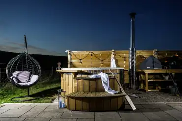 White Clover ensuite pod wood-fired hot tub with fairy lights at night