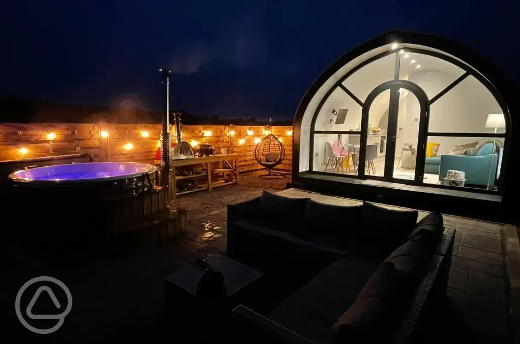 White Clover pod at night with lights and a private wood-fired hot tub