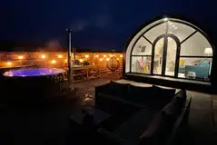 White Clover pod at night with lights and a private wood-fired hot tub White Clover pod at night with lights and a private wood-fired hot tub