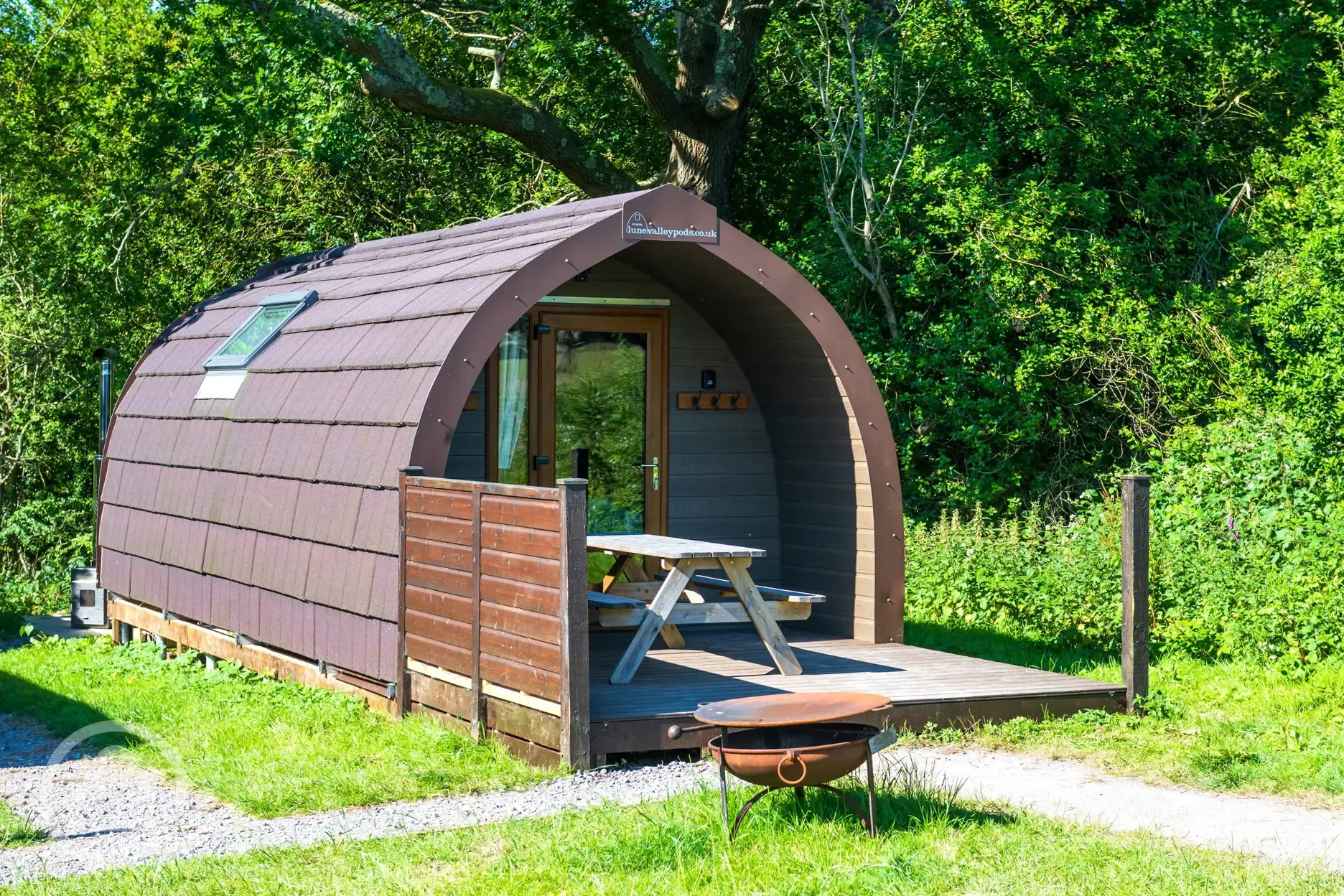 Ensuite glamping pod exterior with outdoor bench seating and firepit