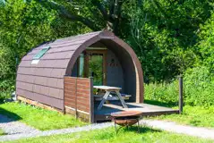 Ensuite glamping pod exterior with outdoor bench seating and firepit
