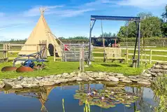 Tipi tent exterior with pond and swing Tipi tent exterior with pond and swing