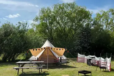 Bell tent with a fire pit and picnic bench at Goldstone Camping
