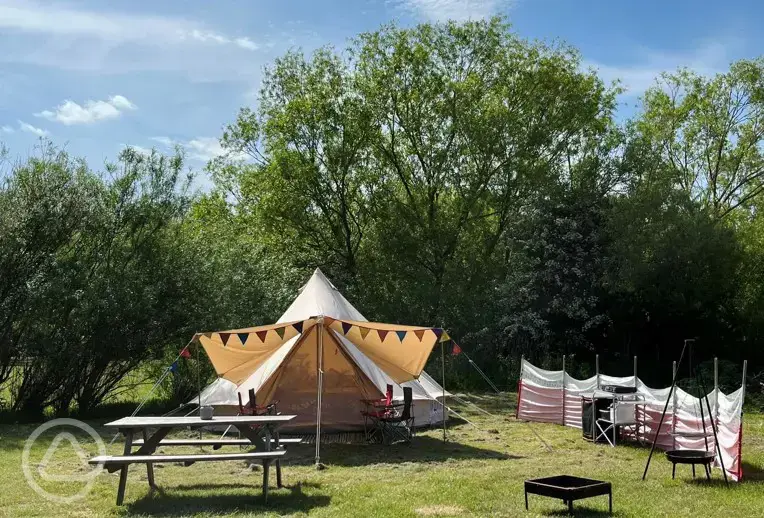 Bell tent with a fire pit and picnic bench at Goldstone Camping