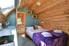 Glamping pod interior with a king size bed, bedding, towels and ensuite