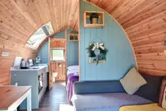 Glamping pod interior with an L-shaped sofa bed and half dividing wall