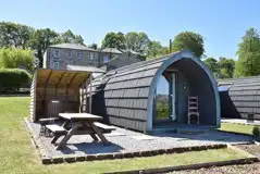 Glamping pod with a covered wood-fired hot tub and picnic bench