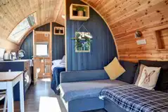 Glamping pod interior with an L-shaped sofa bed and half dividing wall