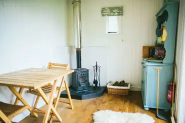 Hut interior, woodburner, sheepskin rug and welsh dresser