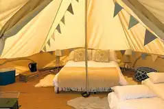 Part furnished bell tents with a double bed and optional airbeds
