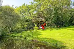 Templar treehouse with a slide and pond at Melin Mabes