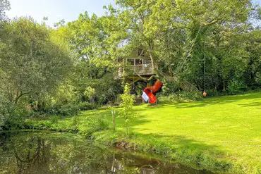 Templar treehouse with a slide and pond at Melin Mabes