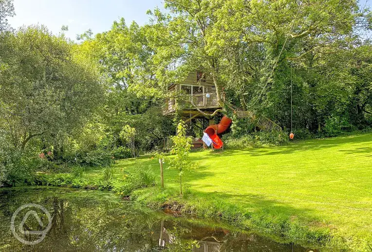 Templar treehouse with a slide and pond at Melin Mabes