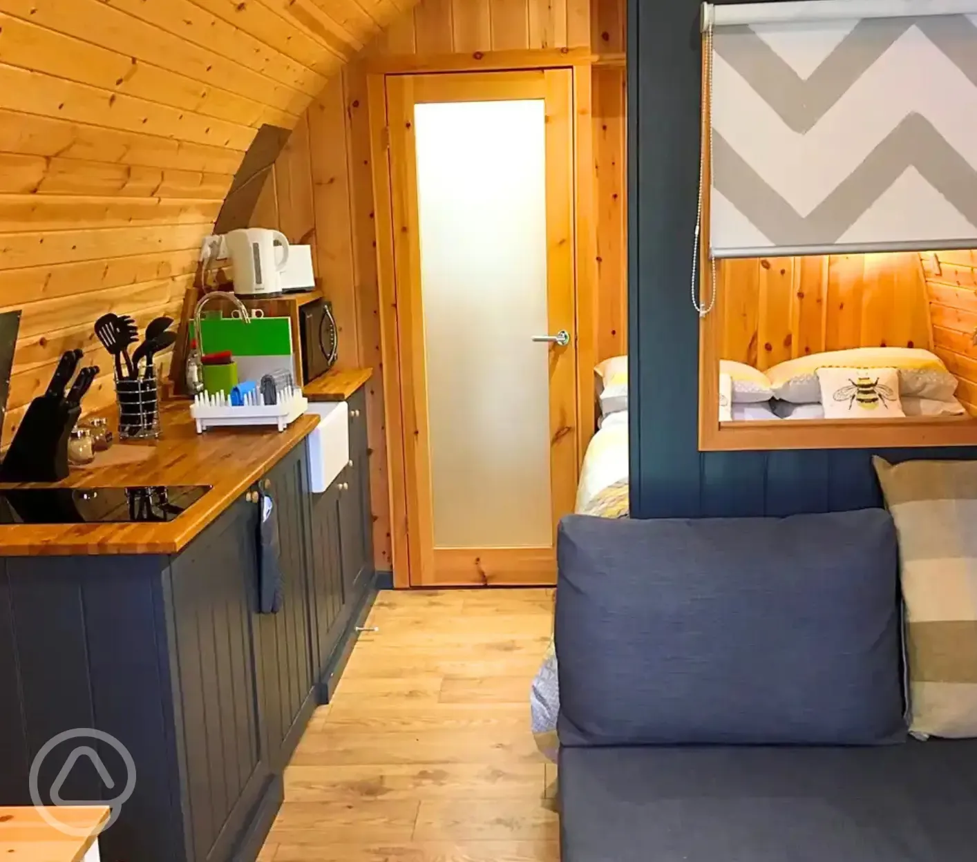 Pod interior with lounge area, bed, kitchenette and door to the ensuite bathroom