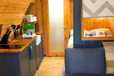 Pod interior with lounge area, bed, kitchenette and door to the ensuite bathroom