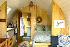 Bowcliffe pod interior with a double bed, bedding, kitchen and ensuite