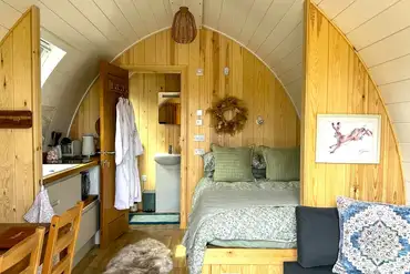 Bowcliffe pod interior with a double bed, bedding, kitchen and ensuite