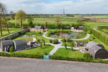 Four glamping pods set around a wildlife pond